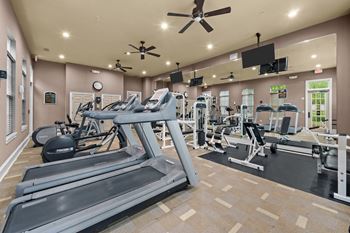 a gym with cardio equipment and a ceiling fan